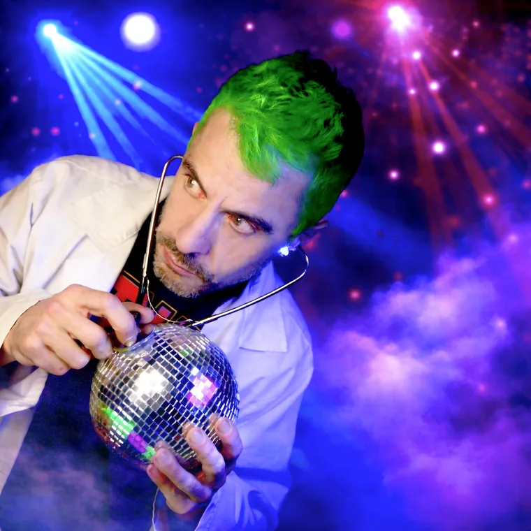El Dr. Caudevilla, con bata y estetoscopio, ausculta una bola de discoteca bajo luces de colores