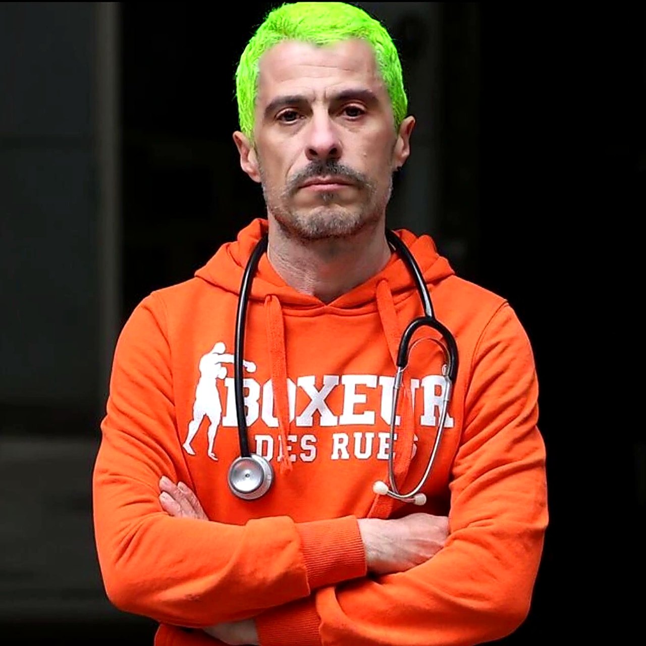 Retrato del Dr. Fernando Caudevilla con sudadera naranja y fonendoscopio.